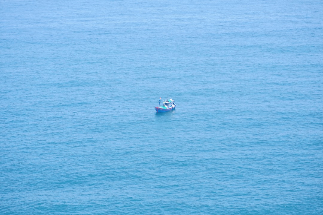 Angler on an offshore charter boat, rod bent dramatically, fighting a large fish in the deep blue sea.