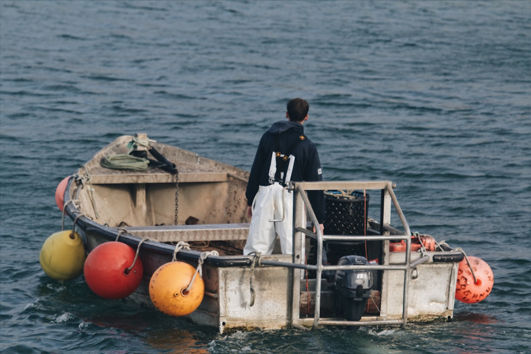 A proud fisherman holding a very large yellowfin tuna on the deck of a deep-sea fishing boat with the ocean in the background.