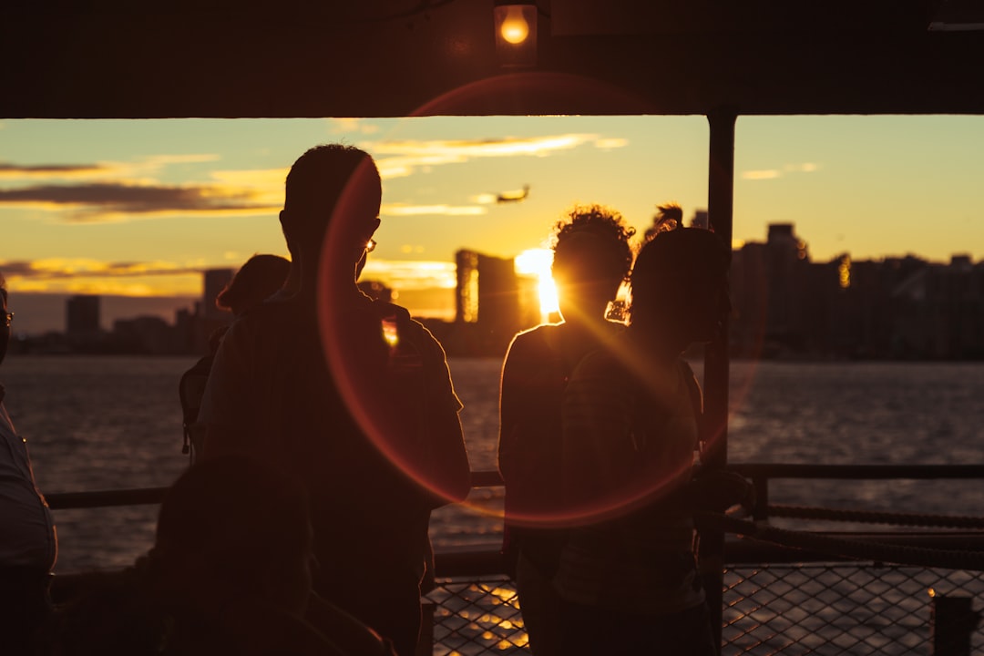 Group of diverse friends laughing and having fun together on a pontoon boat on a sparkling lake under a bright, sunny sky.