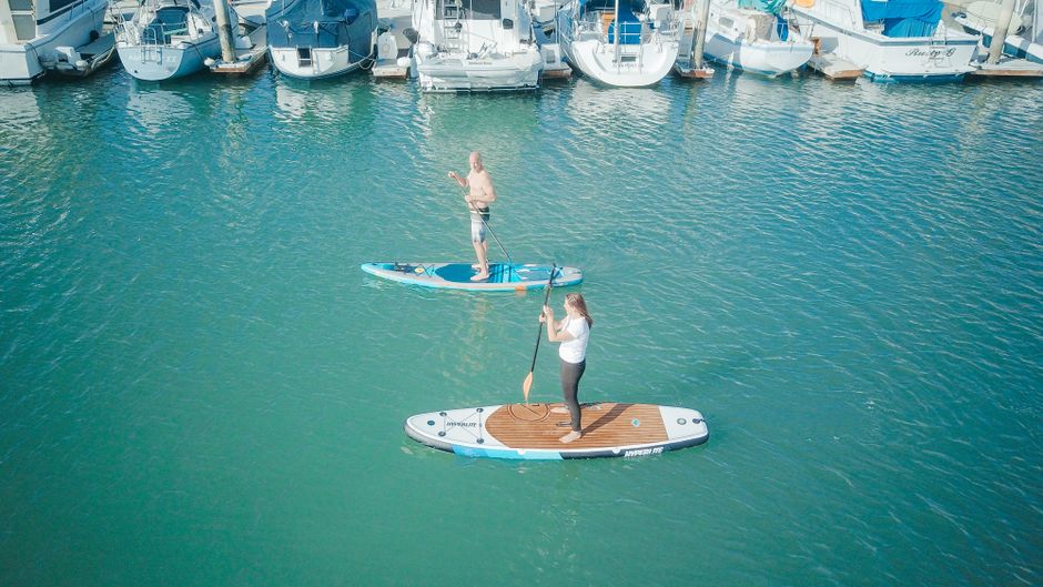 Group of friends enjoying a sunny day by paddleboarding on a wide, calm river, representing an active and social waterfron...