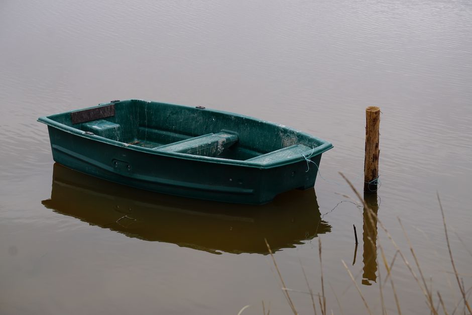 A single small boat navigates choppy waters on a lake, representing the challenges of using the traditional 6% commission model in today's market.